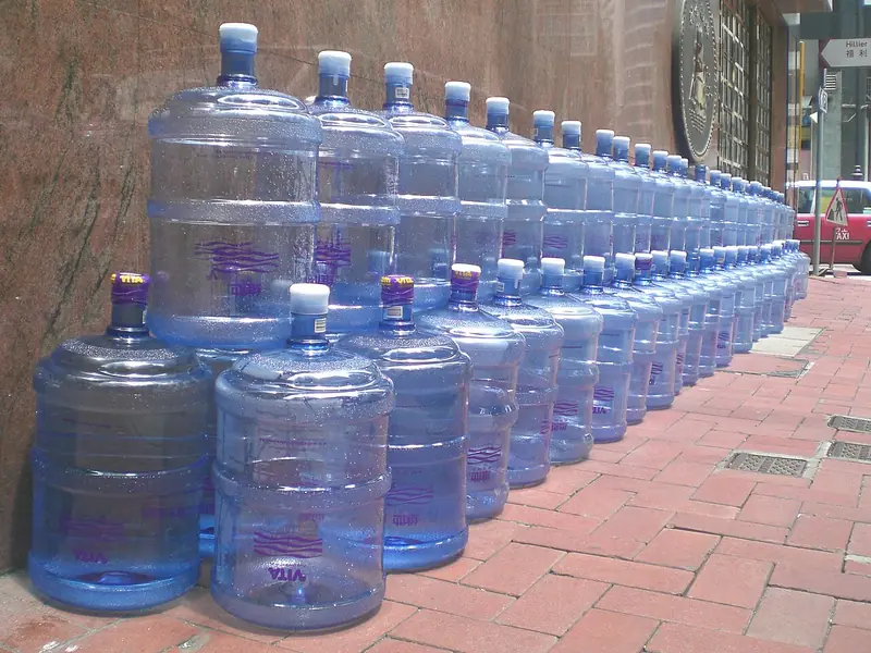 Fileira de galões de água de 20 litros numa calçada