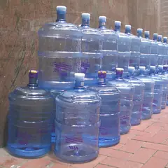Fileira de galões de água de 20 litros numa calçada
