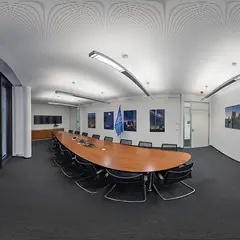 Sala de reuniões com mesa oval e telas
