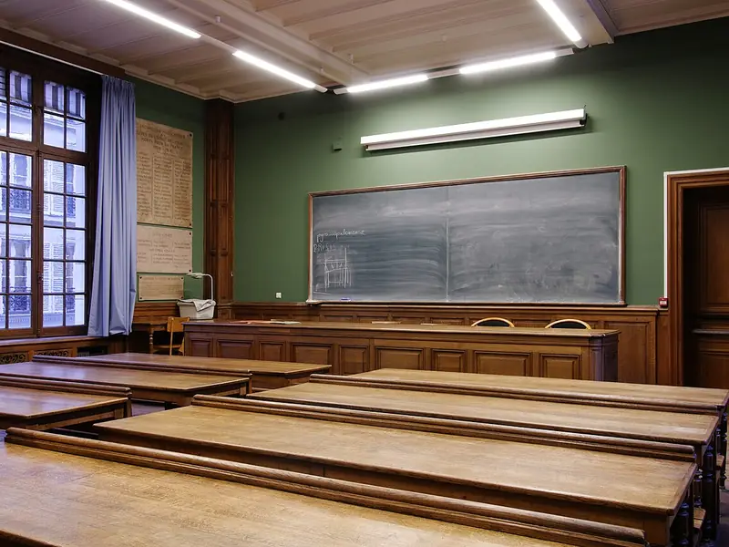 Sala de aula com carteiras de madeira e quadro-negro