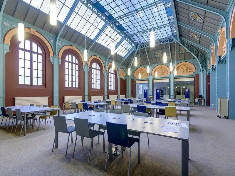 Biblioteca com mesas de estudo sob uma cobertura de vidro