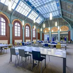 Biblioteca com mesas de estudo sob uma cobertura de vidro