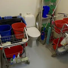 Carrinho de limpeza com baldes e materiais em um banheiro