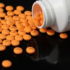 Comprimidos espalhados ao lado de um frasco