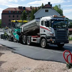 Caminhão abastecendo a vibroacabadora durante o asfaltamento