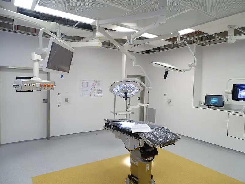 Sala de cirurgia moderna e vazia, com mesa e focos de luz